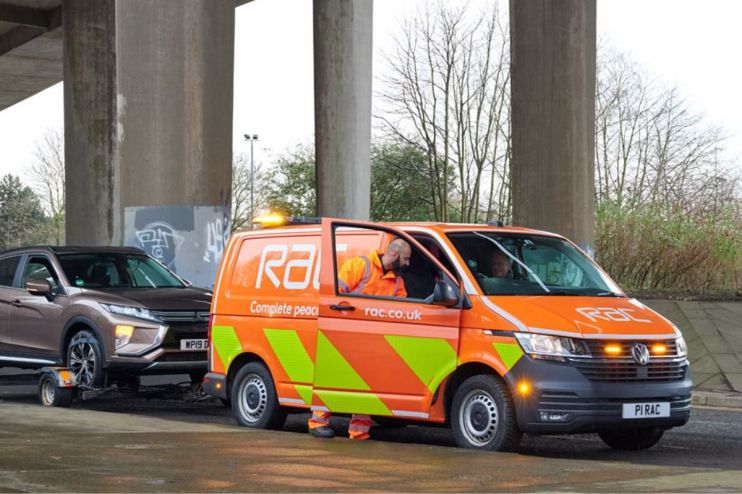 RAC breakdown recovery van with an open door, a technician in a high-vis jacket, and a car being towed.