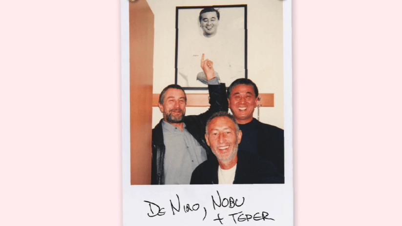 Robert De Niro, Nobu Matsuhisa, and Meir Teper smiling in a Polaroid, with a framed picture in background