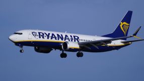 Ryanair Boeing 737 aircraft in flight with landing gear extended against a clear blue sky