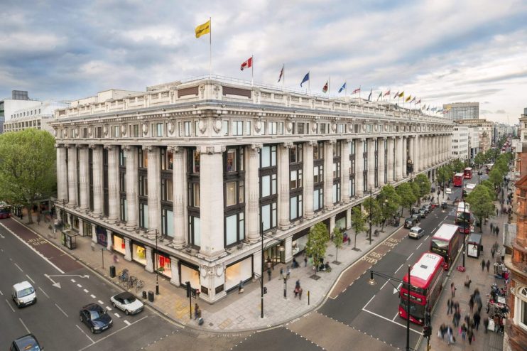 Aerial view of the Selfridges building on Oxford Street, London, with street traffic and pedestrians below.