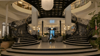 Grand black and white spiral staircase in the elegant lobby of Six Senses London, with seating area and plants.