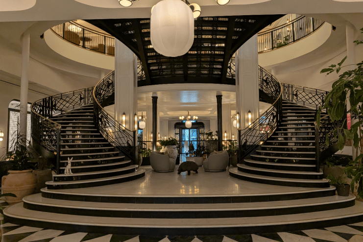 Grand black and white spiral staircase in the elegant lobby of Six Senses London, with seating area and plants.