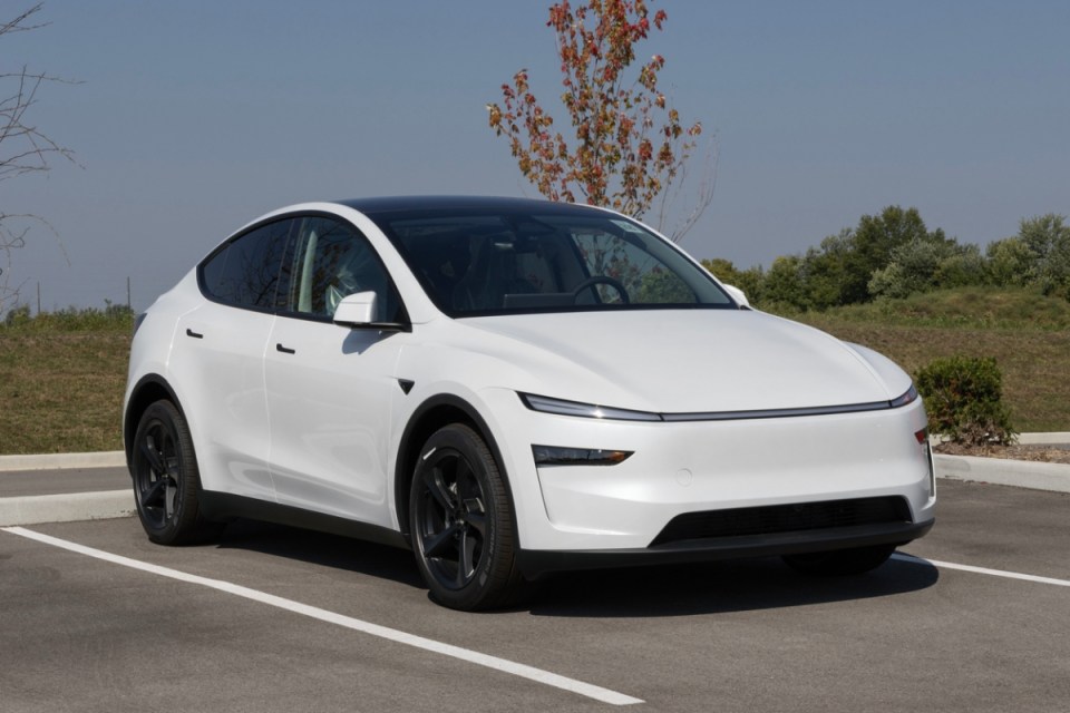 White Tesla Model Y electric SUV parked outdoors with a black roof and wheels.