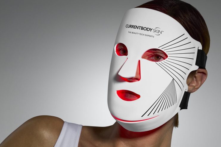 CURRENTBODY Skin LED face mask on a person, highlighting the red light therapy for beauty tech applications.