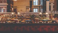 Lavish buffet spread at The Ned with diverse dishes, fresh salads, and a full bar in a grand, historic interior.