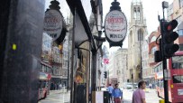 El Vino wine merchant sign on a busy London street with a red double-decker bus and church steeple.