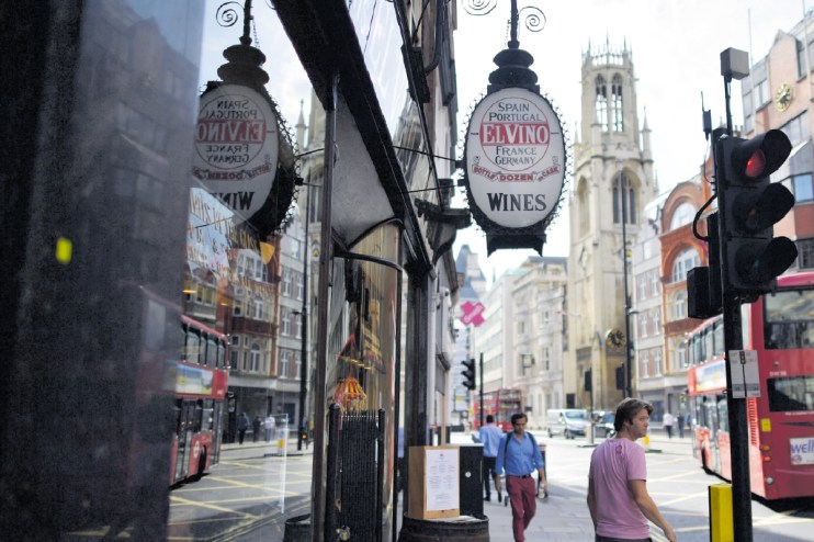 El Vino wine merchant sign on a busy London street with a red double-decker bus and church steeple.