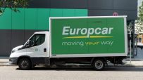 White Europcar moving truck with green side panel and moving your way slogan parked on a street.