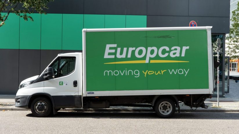 White Europcar moving truck with green side panel and moving your way slogan parked on a street.