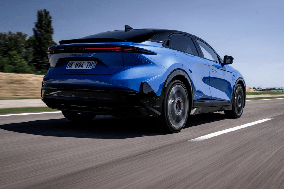 Blue Alpine A290 GT electric hot hatch driving on a highway, rear view.