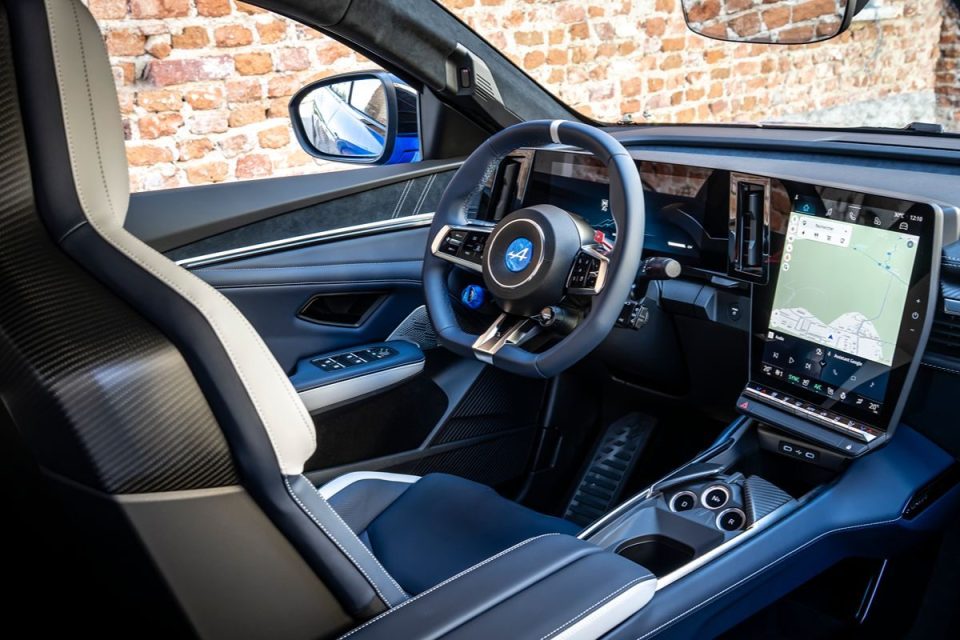 Modern car interior with blue and white racing seats, a multifunctional steering wheel, and a large central touchscreen di...