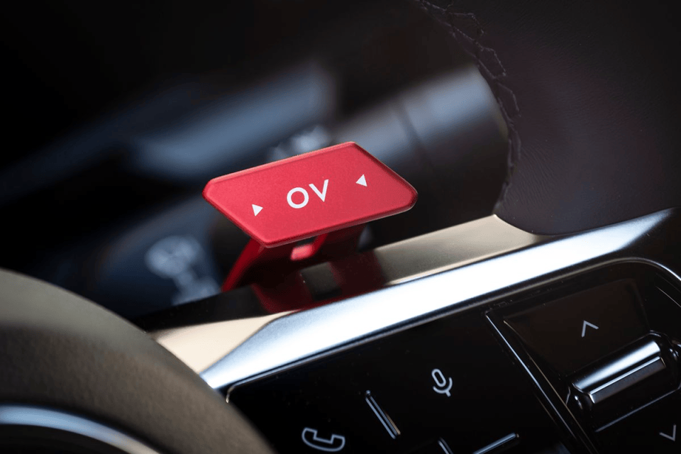 Close-up of a red OV button on a cars steering wheel, with control buttons below