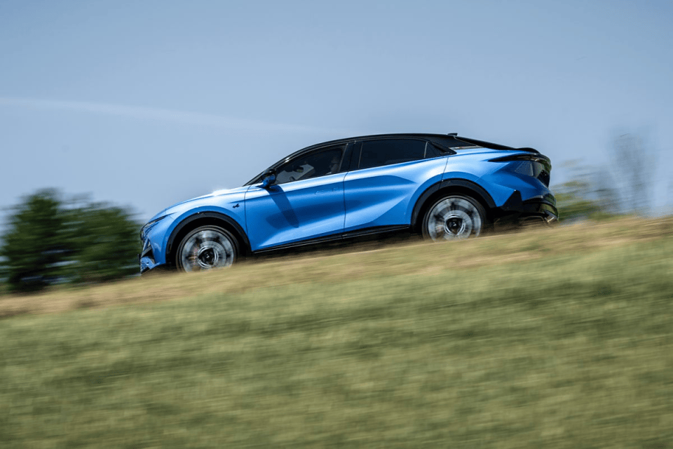 Dynamic blue electric vehicle driving uphill on a grassy slope with blurred background motion
