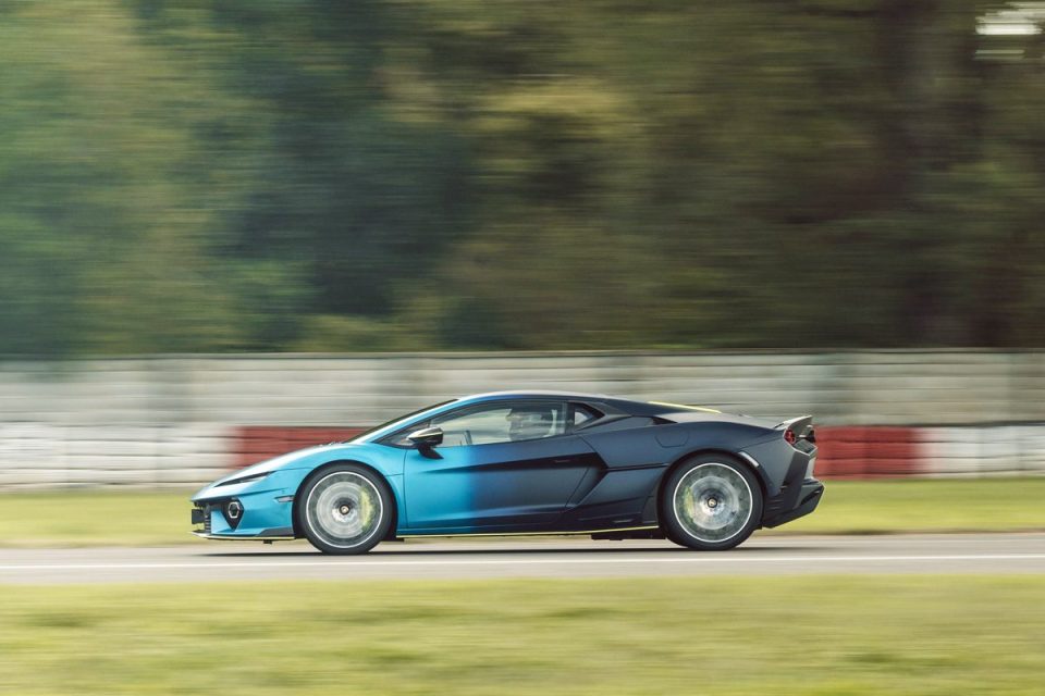 Sleek blue and black sports car speeding on a race track with blurred background, showcasing motion and design.