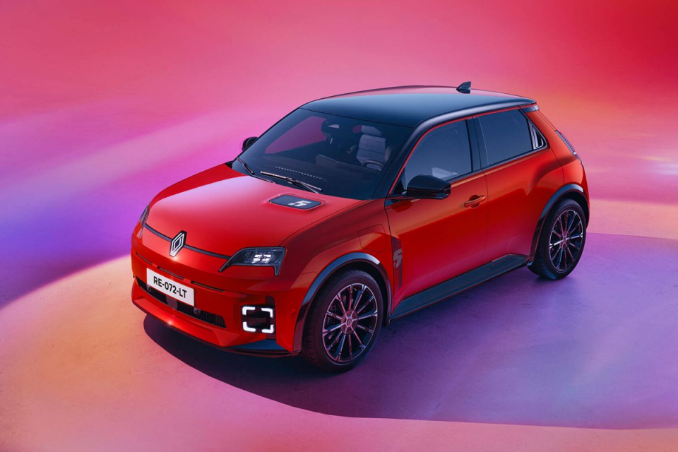 Sleek red Renault 5 Prototype electric car with black roof and wheels, parked on a vibrant pink and purple surface.