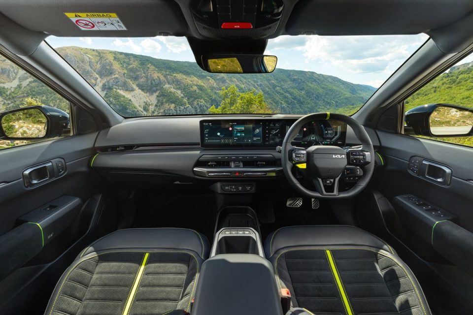 Interior of a modern car with a dashboard, steering wheel, seats, and mountain landscape visible through the windshield.