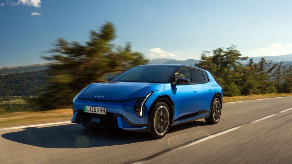 Blue Kia EV6 electric vehicle driving on a winding road with trees and mountains in the background