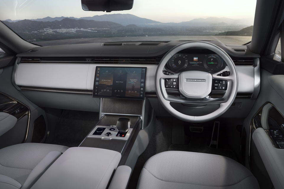 Modern Range Rover interior with a large touchscreen infotainment system, digital dashboard, and panoramic mountain view.