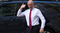 John Healey, wearing a white shirt and red tie, exits a vehicle, possibly discussing fiscal headroom.