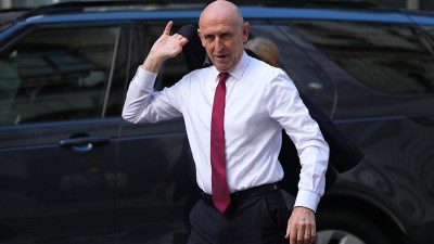 John Healey, wearing a white shirt and red tie, exits a vehicle, possibly discussing fiscal headroom.