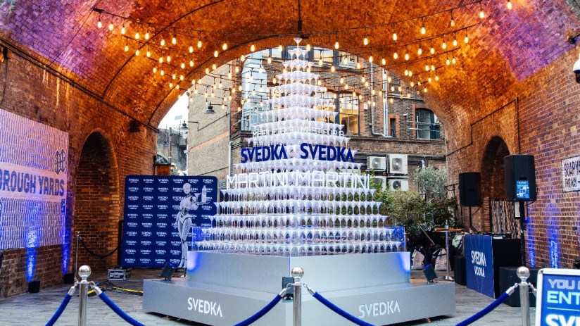 SVEDKA Martini pyramid display under string lights in an archway with Borough Yards banner
