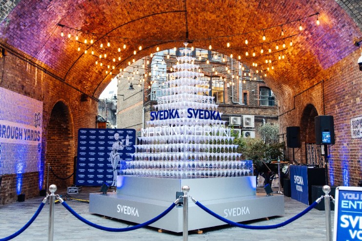SVEDKA Martini pyramid display under string lights in an archway with Borough Yards banner