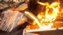 Molten metal pouring from a crucible into a mold, glowing orange in a metallurgy foundry.