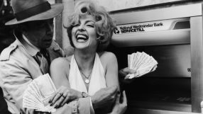 Smiling woman holding cash with a man in a trench coat at a National Westminster Bank ATM