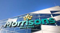 Morrisons supermarket sign on a modern building facade against a clear blue sky, highlighting the brand logo.