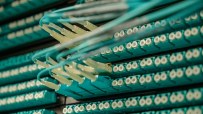 Close-up of fiber optic cables and connectors in a server rack, illustrating data center technology and connectivity.