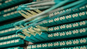 Close-up of fiber optic cables and connectors in a server rack, illustrating data center technology and connectivity.