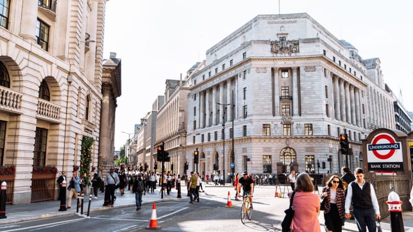 Busy street scene in London with historic buildings, pedestrians, traffic, and a Bank Underground station sign.