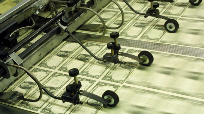 Sheets of newly printed US one-dollar bills moving along a printing press production line.