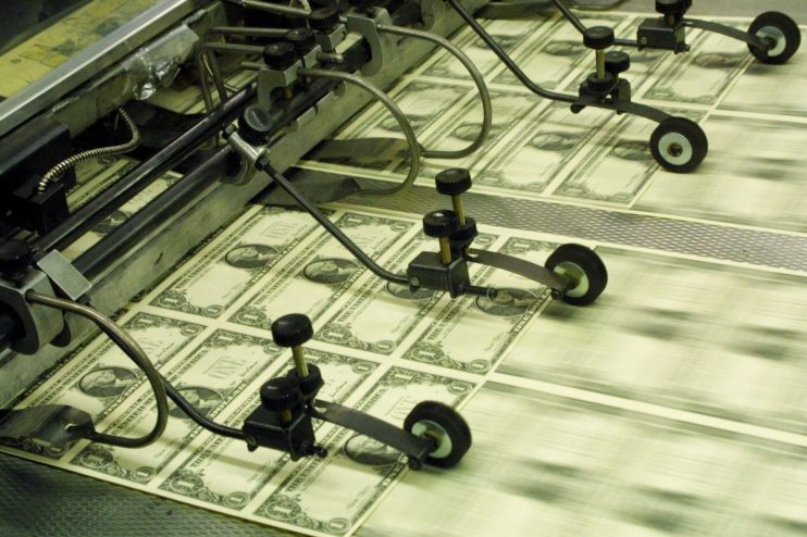 Sheets of newly printed US one-dollar bills moving along a printing press production line.