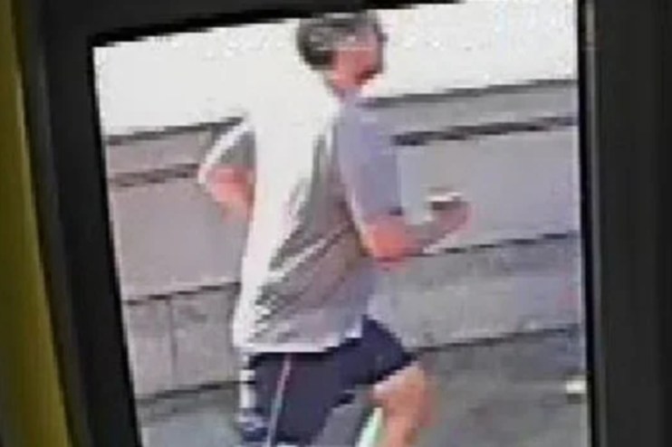 CCTV footage of the Putney Pusher, a man in a grey shirt and black shorts, running past a wall.
