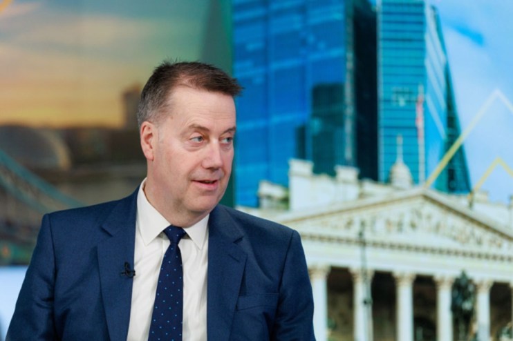 Standard Life CEO Andy Briggs in a blue suit, looking right, with city buildings in background