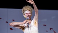Tilda Swinton performing in Man to Man with dramatic makeup, spiky hair, holding a microphone.