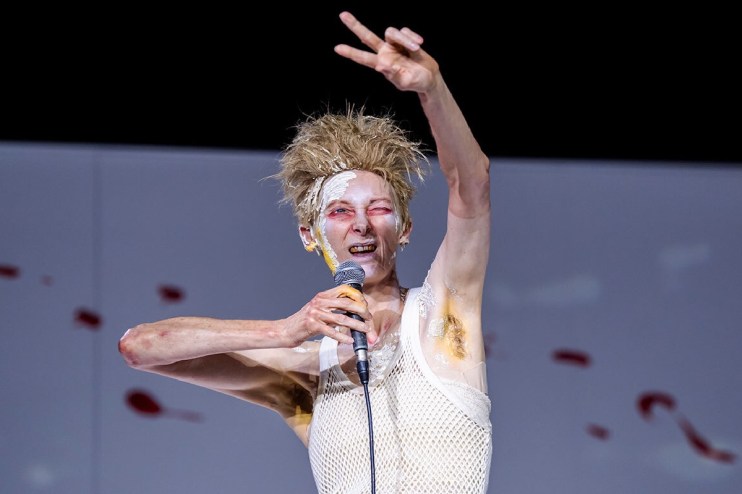 Tilda Swinton performing in Man to Man with dramatic makeup, spiky hair, holding a microphone.