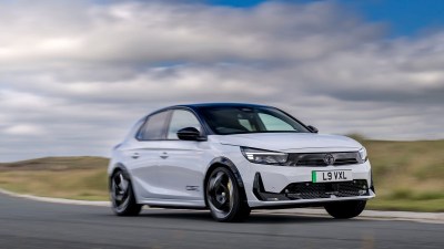 White Vauxhall Corsa driving on a winding road under a cloudy sky