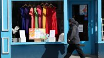 A person walks past a closed shop window displaying colorful clothes and Hope, Love signs with rainbows