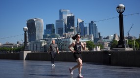 Woman jogging on a promenade with the London skyline, including the Walkie-Talkie building, in the background.