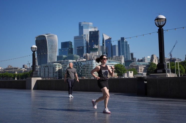 Woman jogging on a promenade with the London skyline, including the Walkie-Talkie building, in the background.