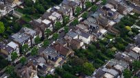 Aerial view of a dense residential neighborhood with houses, gardens, and streets, showcasing urban planning.