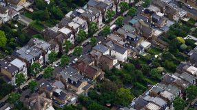 Aerial view of a dense residential neighborhood with houses, gardens, and streets, showcasing urban planning.