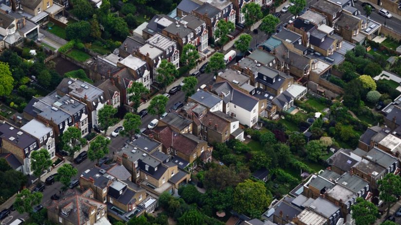 Aerial view of a dense residential neighborhood with houses, gardens, and streets, showcasing urban planning.