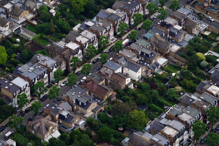 Aerial view of a dense residential neighborhood with houses, gardens, and streets, showcasing urban planning.