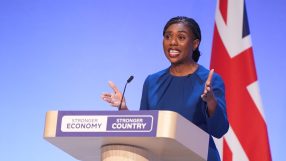 Kemi Badenoch speaking at a podium with Stronger Economy, Stronger Country text and a Union Jack flag.