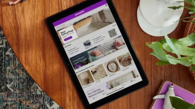 Tablet displaying Wayfair e-commerce website with home decor items on a wooden table