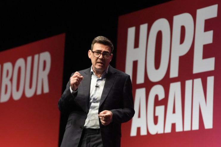 Andy Burnham speaking at the Labour conference, with red HOPE AGAIN and LABOUR banners in background.