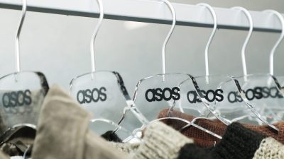 Clear acrylic Asos hangers with black logos holding various garments on a clothing rail